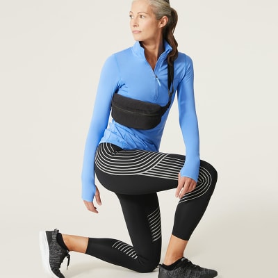 Woman wearing Goodmove Go Perform black compression leggings and blue half-zip top. Shop Goodmove