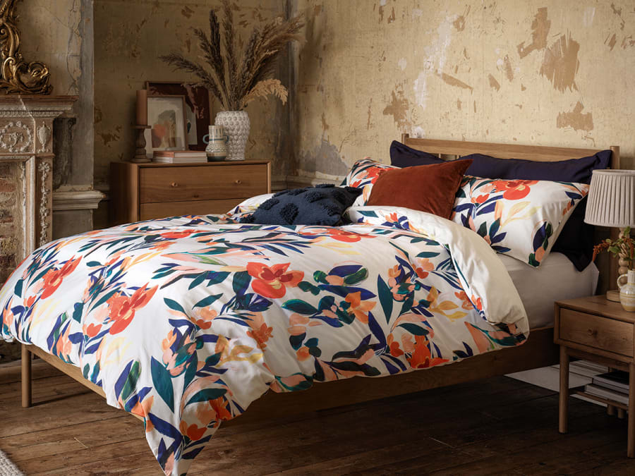 Bed made up with floral-print bedding. Shop bedding