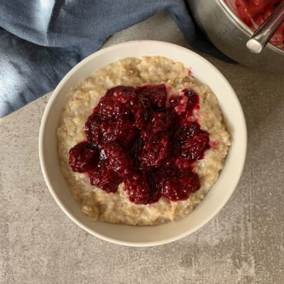 A bowl of porridge topped with frozen fruit