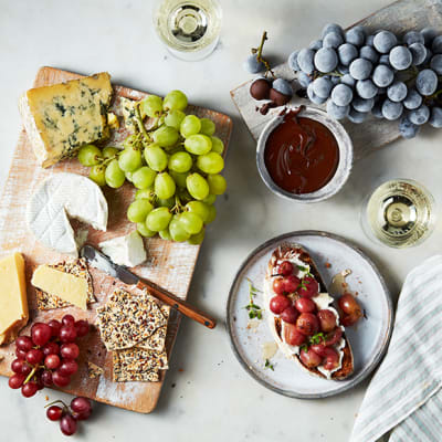 	 A selection of cheeses served alongside bunches of grapes