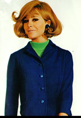 Woman wearing a blue wool skirt suit with a green top, 1967