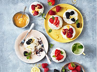 Plates of fruit-topped meringues and fresh berries