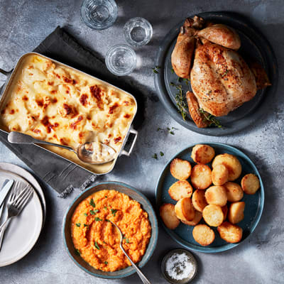 Roast chicken with cauliflower cheese, goose-fat potatoes, and carrot and swede crush