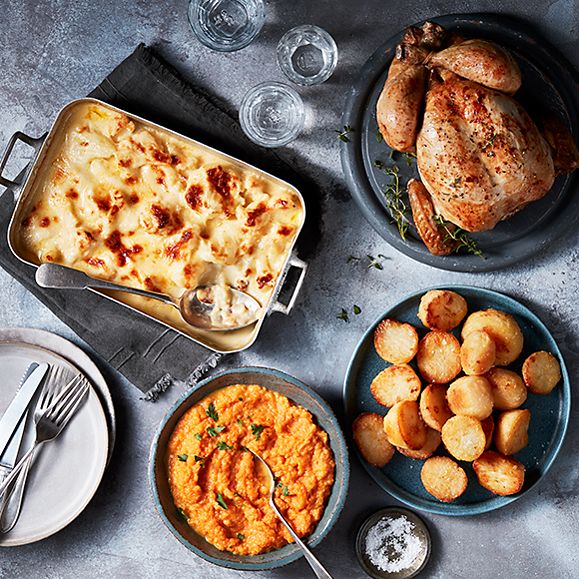 Roast chicken with cauliflower cheese, goose-fat potatoes, and carrot and swede crush
