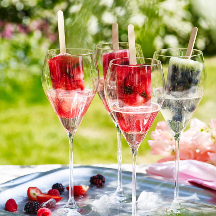 Wine glasses of fruit ice lollies and prosecco in a summer garden