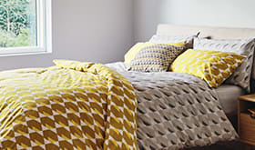 Grey and yellow bedding on a bed