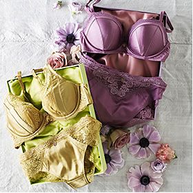 One green lingerie set and one lilac lingerie set from the Rosie for Autograph collection on a table with flowers scattered around