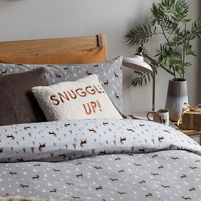 Bed made up with grey stag-print bedding, cosy cushions and a throw