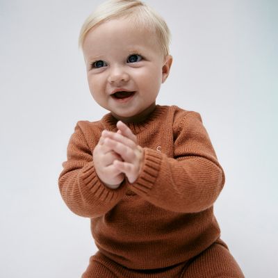 Baby wearing brown knitted outfit. Shop baby new in