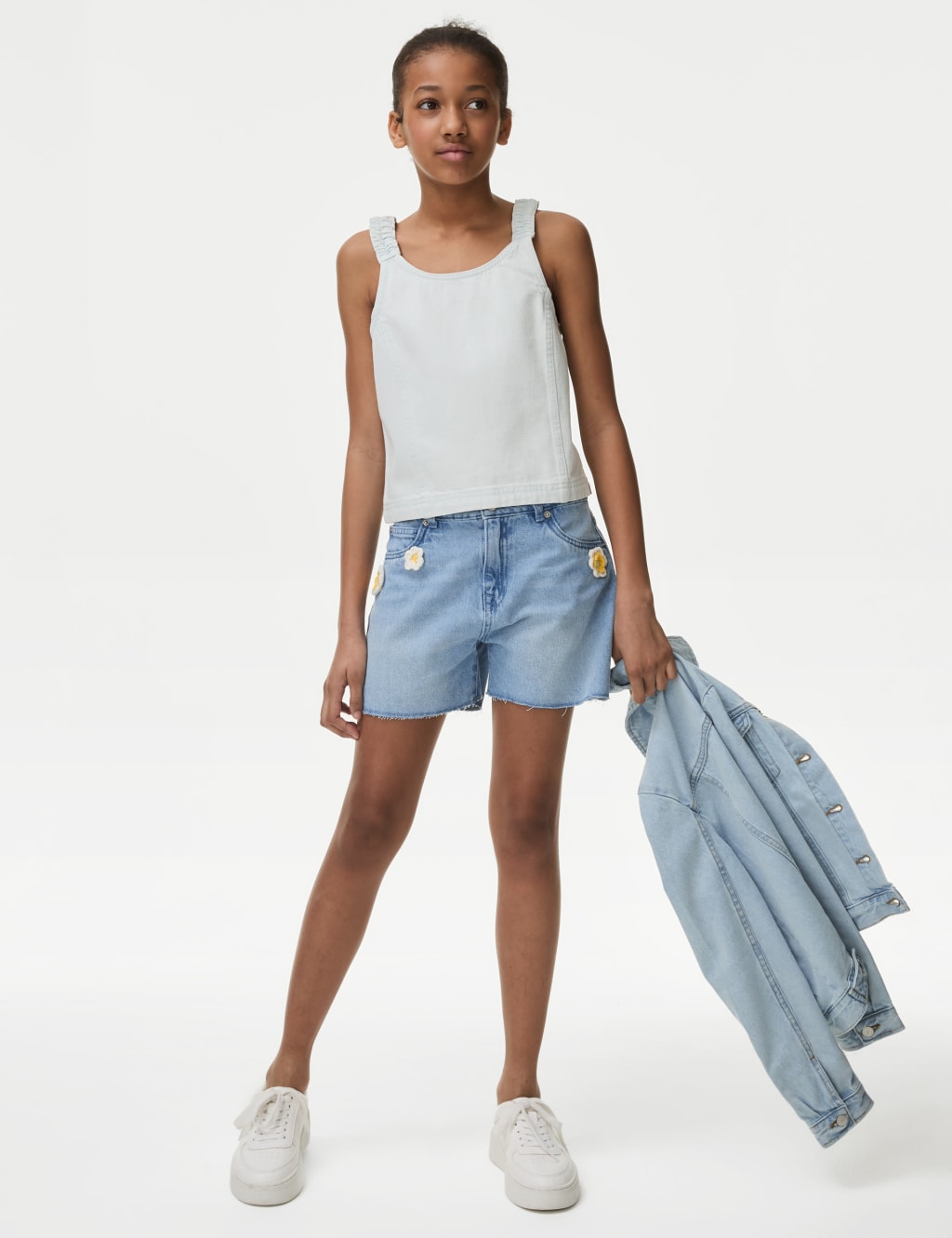 Woman in white tank top and blue denim shorts wearing black cap