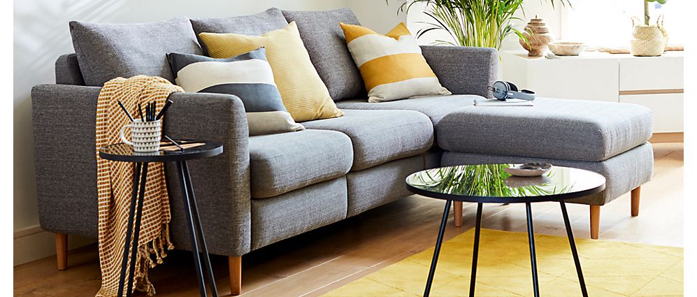 Grey corner sofa with striped cushions and rug