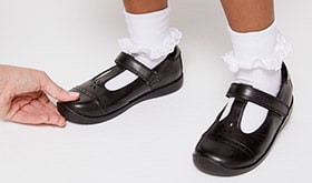 Adult applying gentle pressure to top of child's shoe