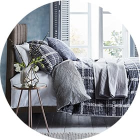Checked bed set next to a contemporary bedside table