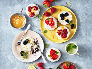 Meringue nests filled with cream, lemon curd and fresh berries