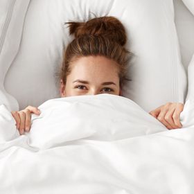 Woman in bed under white bedding