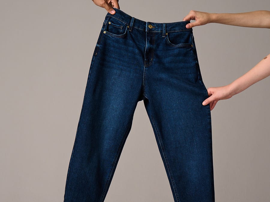 Two hands holding a pair of jeans. Read more about our denim